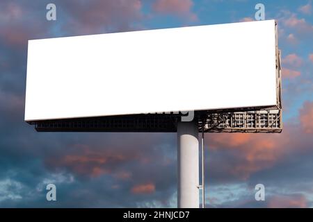 Mock up - blank wide white billboard against warm sunset sky with clouds Stock Photo