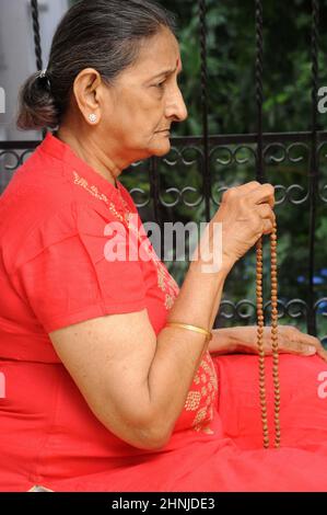 Mumbai Maharashtra India Asia June 29 2021 Morning prayer Indian old hindu woman praying Mala beads. Stock Photo