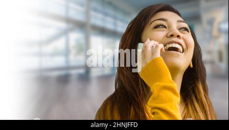 Young asian woman laughing while talking on smart phone Stock Photo