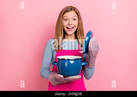 Portrait of attractive cheerful funny amazed girl cooking domestic cuisine soup isolated over pink pastel color background Stock Photo