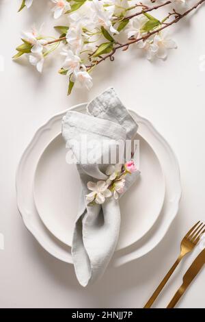Easter table setting with spring flowers on white background. Top view. Festive tablescapes. Vertical format. Stock Photo