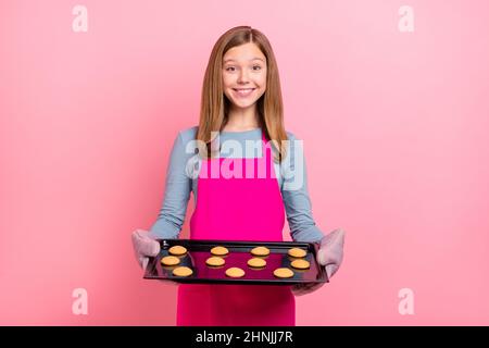 Portrait of attractive trendy funny cheery girl preparing fresh homemade cookies isolated over pink pastel color background Stock Photo