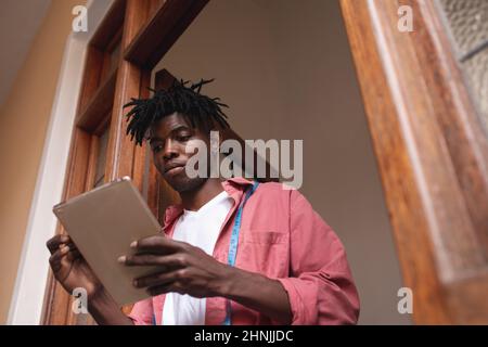Low angle view of african american young male owner using digital table at store entrance Stock Photo