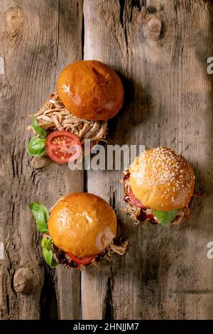 Set of homemade mini burgers with stew beef, tomatoes and basil on wooden background. Modern delicious fast food. Flat lay, copy space Stock Photo