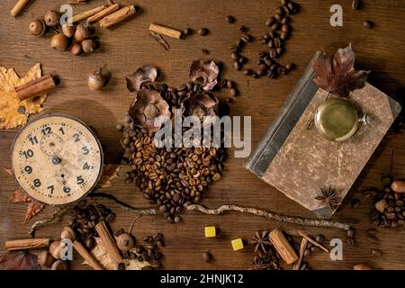 Owl shape from coffee beans and spices. Owl sit on the branch with vintage clock, playing cards, dice over wooden background. Funny mystery coffee pre Stock Photo