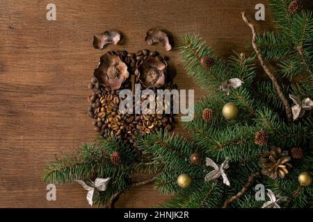 Owl shape from coffee beans and spices. Owl sit on fir Christmas tree branch with natural decor over wooden background. Funny mystery xmas coffee conc Stock Photo