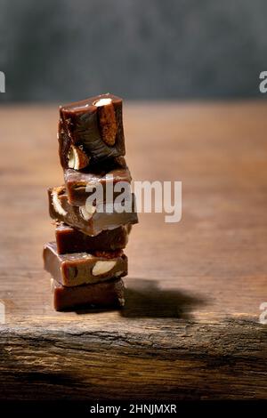 Stack of homemade toffee salted caramel chocolate almond nuts candy on wooden table. Handmade food sweet gifts for any holidays. Stock Photo