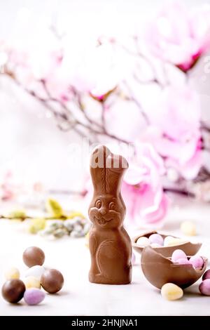 Easter greeting card with chocolate sweets rabbit, candies and eggs, spring blossom branches on white background. Easter treats Stock Photo