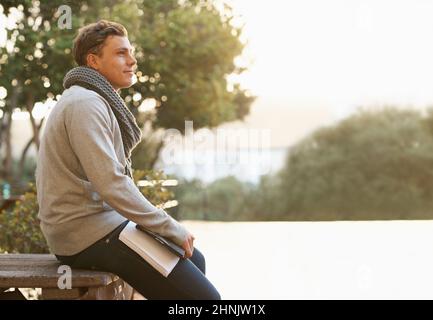 So much to achieve. Shot of a thoughtful young male student leaning on a campus bench. Stock Photo