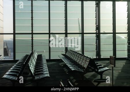 a deserted airport, empty benches by a panoramic window, a huge plane visible through the glass walls of an interchange hub in the United Arab Stock Photo