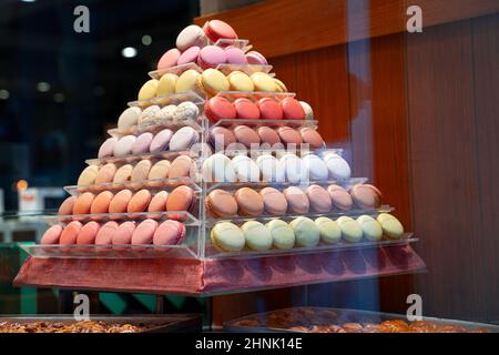 side view closeup of colorful assorted macarons cakes arranged in pyramid shape in candy store window Stock Photo