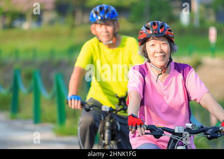 Happy  senior couple exercising with bicycles in the park Stock Photo