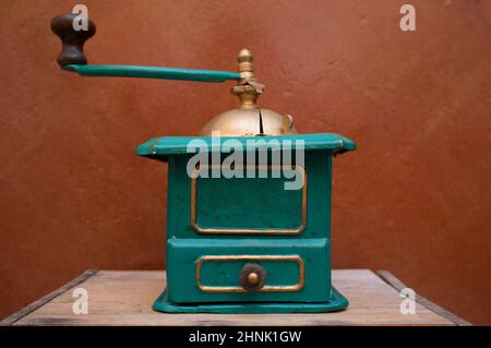 Old manual coffee grinder painted gold and green. Selective focus Stock Photo