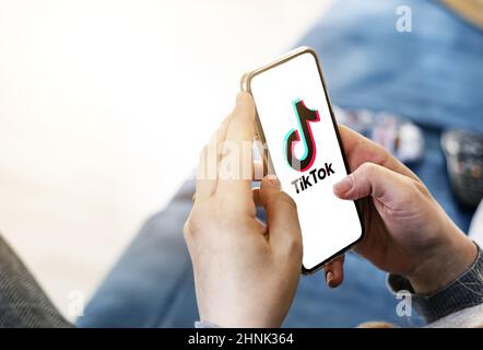 Woman holding a smart phone with TikTok app on the screen Stock Photo