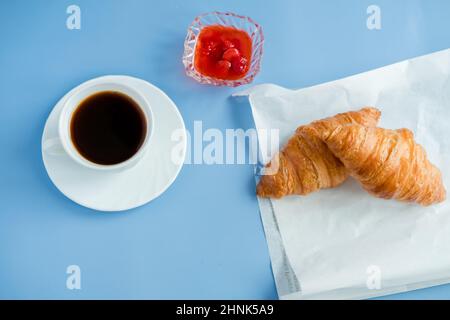 Croissants with jam and morning coffee flat lay. Isolated on blue background. Stock Photo
