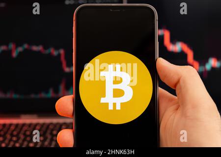 Bitcoin SV BSV app of cryptocurrency stock market analysis on the screen of mobile phone in man hands and downtrend charts trading data on the background, February 2022, San Francisco, USA. Stock Photo