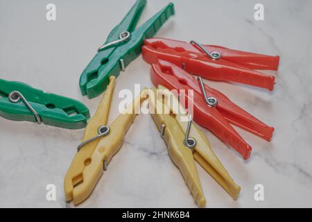Different classic clothespins made of plastic from a surface with marble structure Stock Photo