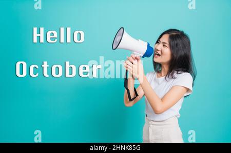 Hello October,  Portrait Asian beautiful young woman standing smile holding and shouting into megaphone looking to text, shoot the photo in a studio i Stock Photo