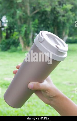 Hand on coffee stainles steel thermo cup, stock photo Stock Photo