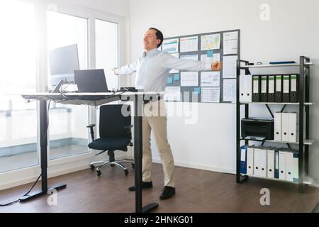 Man Doing Stretch Exercise At Work In Office Stock Photo
