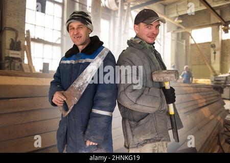 Two bad unskilled builder workers in bad dirty tattered uniform with bad tools. Concept of unskilled workers or crooks or poor quality workers Stock Photo