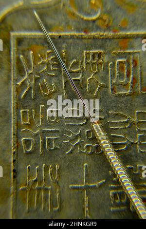 acupuncture needle on antique Chinese coin Stock Photo