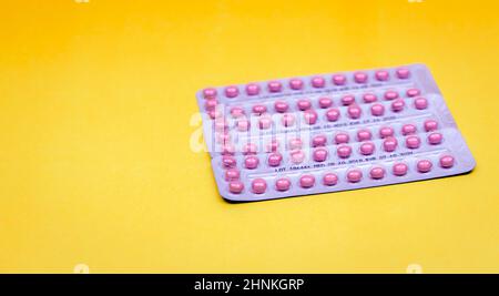 Blister packs of contraceptive pills on yellow background. Hormone pills for treatment hormone acne. Birth control pills. Estrogen and progesterone hormone pills. Pharmacy banner. Prescription drugs. Stock Photo