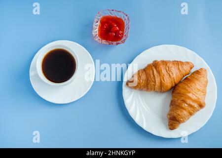 Croissants with jam and morning coffee flat lay. Isolated on blue background. Stock Photo