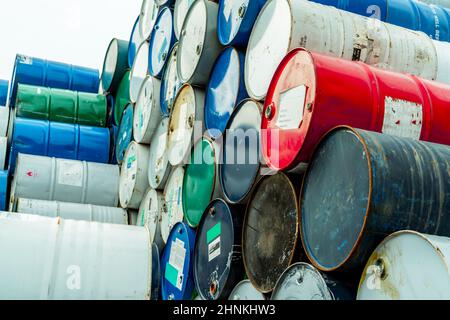 Old chemical barrels with flammable liquid warning label . Steel oil tank. Toxic waste in metal tank. Hazardous chemical barrel. Hazard waste storage in factory. Chemical barrels stack. Oil brent. Stock Photo