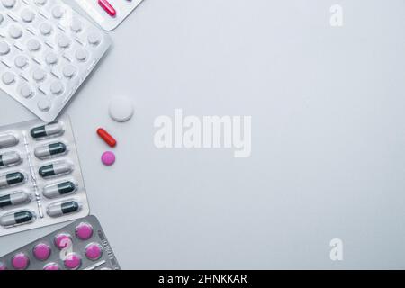 tablets and capsules in the package lie on the side with a handful of tablets on a white background with a place for text in the middle Stock Photo