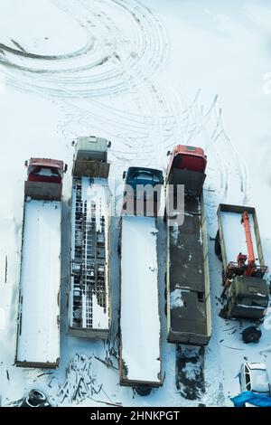 Truck under the snow. lorry covered with snow after snowfall. long trucks stand in a row aerial view. transportation concept. snow covered vehicles. copy space Stock Photo