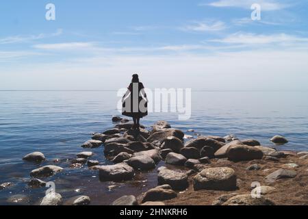 Silhouette of a woman standing on stones at the beach. beautiful summer ...