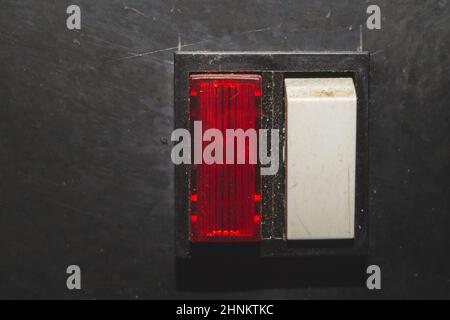 Vintage switch with a red indicator on a black background. white toggle button with red light Stock Photo