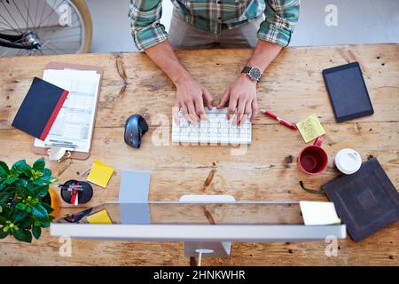 Creative professional at work. Overhead shot of a creative professionals desk while he is typing on his wireless keyboard. Stock Photo