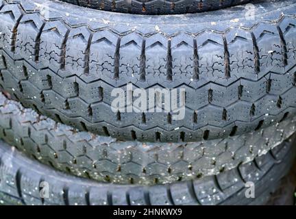 Damaged and worn old black tires on a stack. Damaged and worn old black tires on a stack. Tire tread problems. Solutions concept. Tire tread problems. Stock Photo