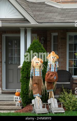 Two dolls and red pumpkins on display in front of the house Stock Photo