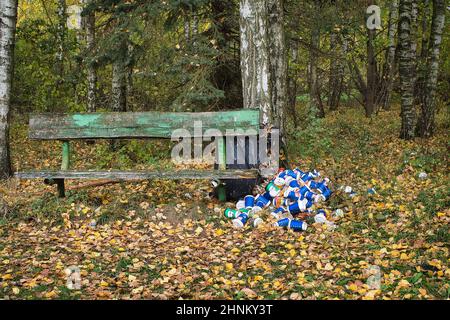 Pile of cans and containers alongside a rustic wooden bench Stock Photo