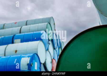 Selective focus on green old chemical barrels stack. Steel tank of flammable liquid. Hazard chemical barrel. Industrial waste. Empty chemical barrels at the factory warehouse. Hazard waste. Stock Photo