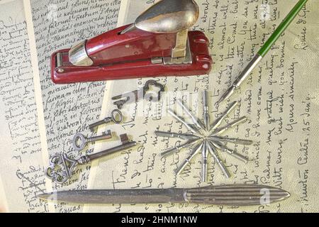 Close-up of accessories on vintage handwriting. Vintage keys, stapler, paper knife, metal nibs and old pen. Vintage stationery. Flat lay Stock Photo