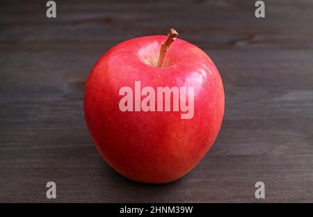 Closeup of a fresh ripe red apple isolated on black wooden backdrop Stock Photo