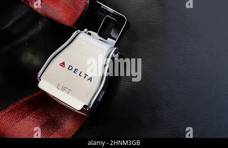 Red lap belt of an empty seat inside an airplane with the Delta Airlines logo printed on the metal. Stock Photo