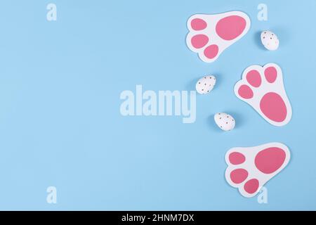 Easter flat lay with cute rabbit feed prints and dotted eggs on blue background Stock Photo