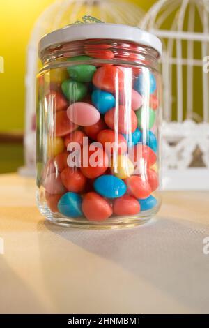 Colorful candied sweets pebbels, displayed in glass jar. Selective focus Stock Photo