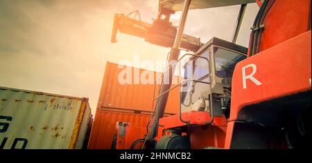 Reach stacker lifting container. Forklift truck handling container at dock. Reach stacker vehicle. Container transport in logistic industry. Cargo and shipping business. Import and export logistic. Stock Photo