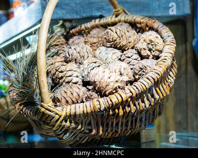 Decorative basket woven from wooden rods is filled with cones. Soft focus Stock Photo