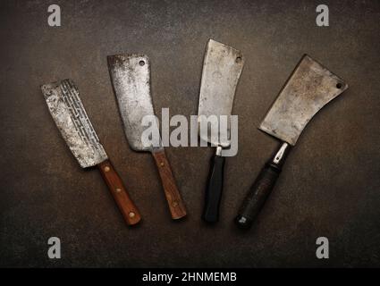 Close up vintage butcher meat cleavers on cutting board or grunge brown stone table surface with copy space, elevated top view, directly above Stock Photo