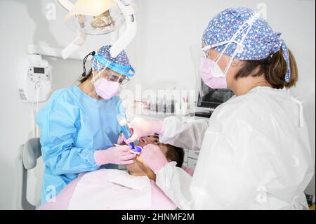 Medical dentist team in dental office treating male patient . Stock Photo