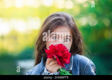Surprised Little cute girl with peony flowers. Child  playing in summer garden. Kids gardening. Children with flower bouquet for birthday or mother s