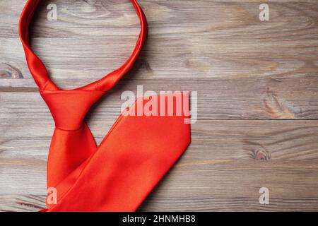 Close-up of a tied solid red business necktie folded on a wooden background with copy space. Formal outfit concept. Stock Photo
