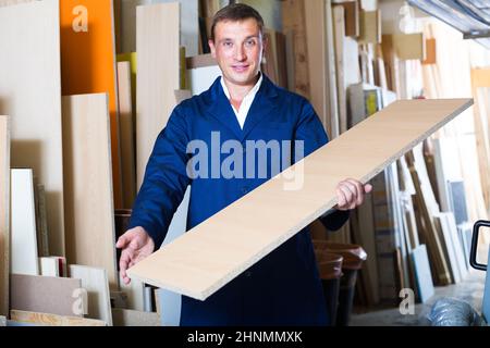 smiling male worker standing with plywood pieces Stock Photo